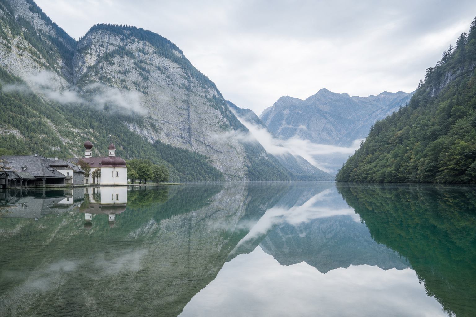 Königssee mit spiegelnder Wasserfläche und bewaldeten Hängen